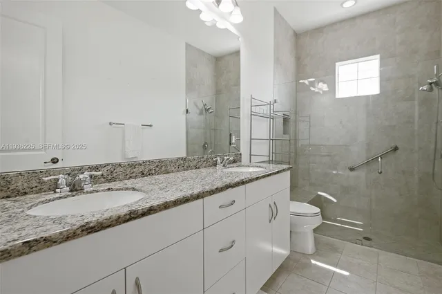 a bathroom with a granite countertop sink a toilet and a mirror
