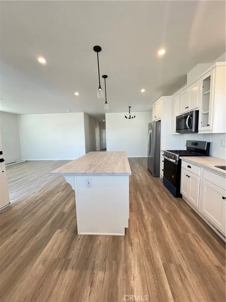 1550 Rimpau, Unit 42 Corona, CA 92881 - Photo 4 of 22 a large kitchen with stainless steel appliances a large counter top a stove a refrigerator with white cabinets and wooden floor