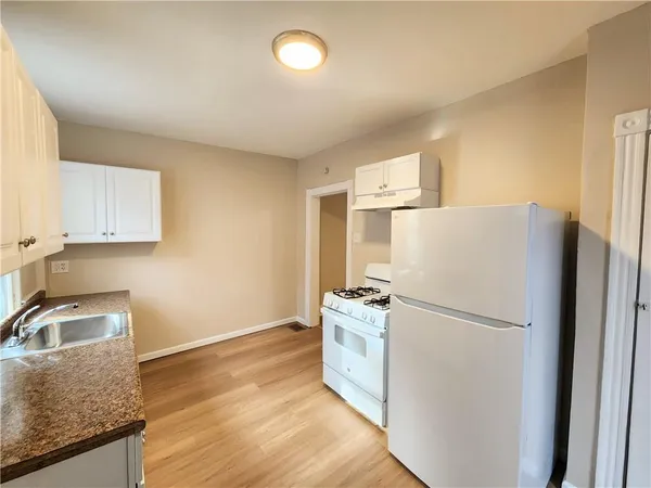 a kitchen with granite countertop a refrigerator a sink a stove and white cabinets