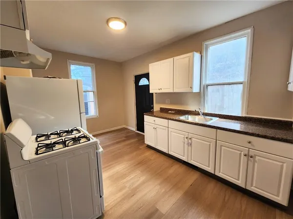 a kitchen with granite countertop a stove a sink dishwasher and a microwave with wooden floor