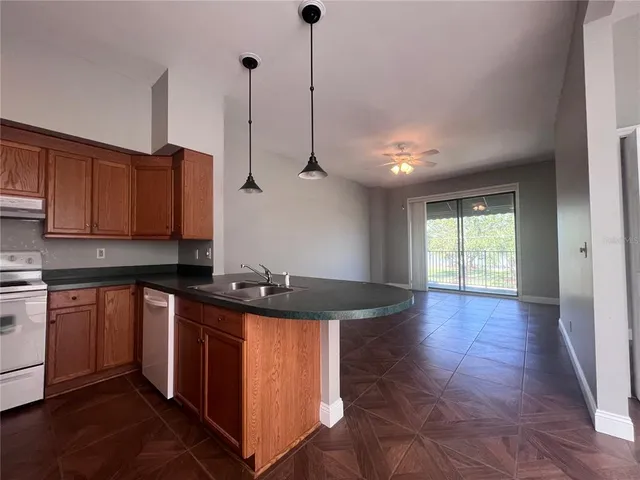 a kitchen with stainless steel appliances granite countertop a sink a stove a refrigerator and island with wooden floor