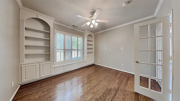 an empty room with wooden floor closet and windows