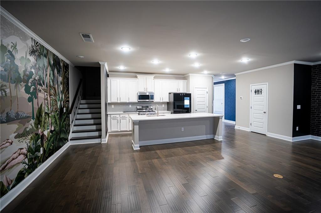 2215 Manor Pointe Drive Cumming, GA 30041 - Photo 4 of 25 a large kitchen with stainless steel appliances a large counter top a stove and a wooden floors