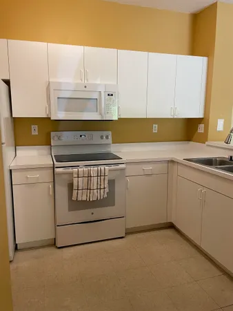 a kitchen with stainless steel appliances a refrigerator a sink and white cabinets