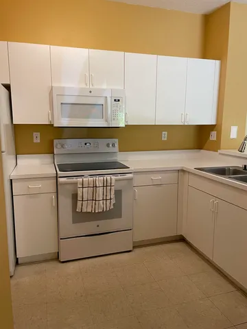 a kitchen with stainless steel appliances a refrigerator a sink and white cabinets