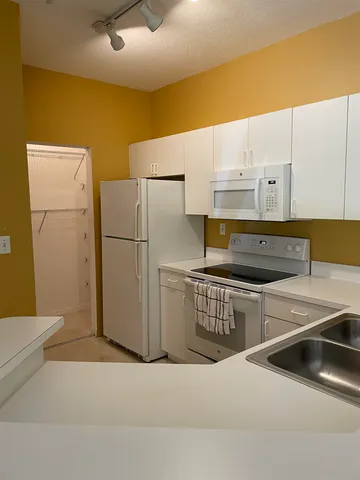 a kitchen with white cabinets and white appliances