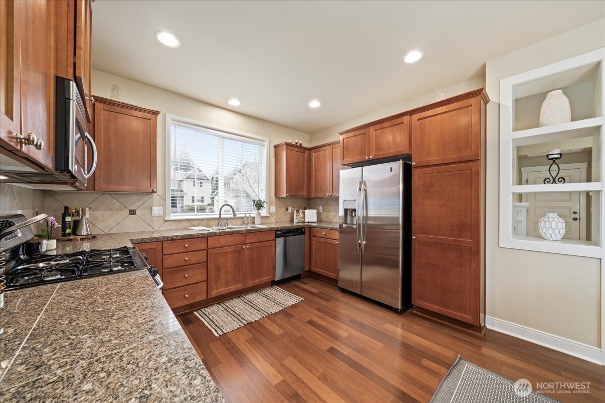 18213 36th Avenue Southeast Bothell, WA 98012 - Photo 14 of 34 a kitchen with stainless steel appliances granite countertop a refrigerator a sink dishwasher a stove with wooden cabinets and floor
