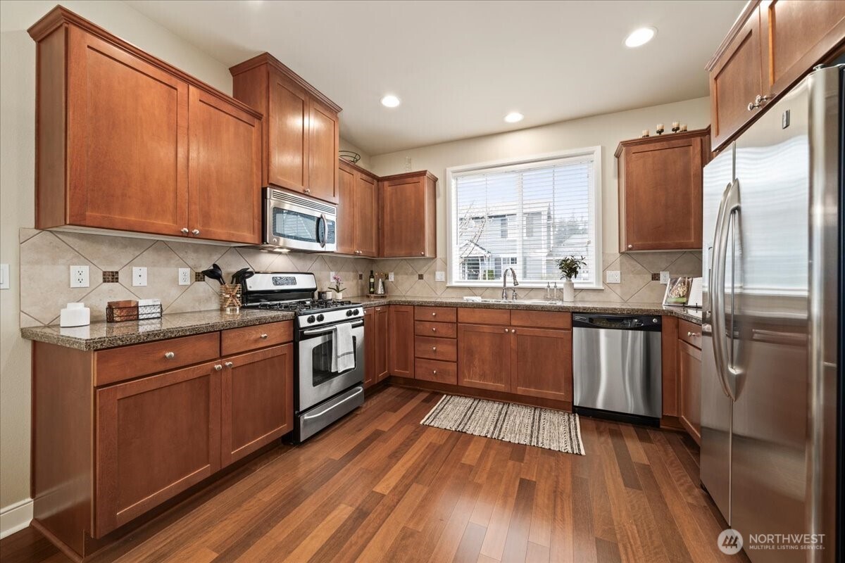 18213 36th Avenue Southeast Bothell, WA 98012 - Photo 8 of 34 a kitchen with stainless steel appliances granite countertop wooden cabinets a refrigerator a sink a stove and a microwave