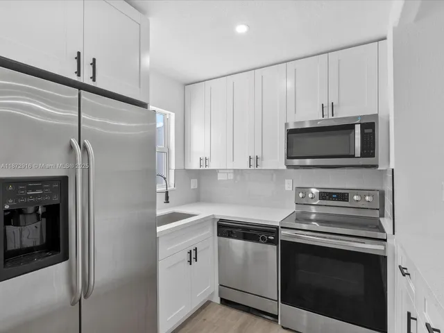 a kitchen with white cabinets and stainless steel appliances