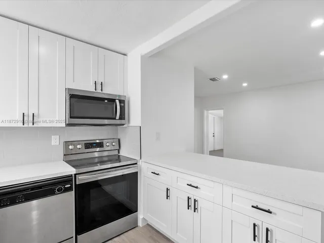 a kitchen with white cabinets and black appliances