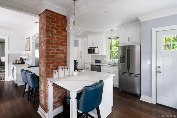 a kitchen with stainless steel appliances granite countertop a dining table chairs refrigerator and cabinets