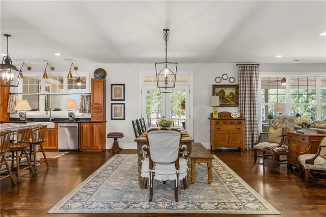 a kitchen with stainless steel appliances kitchen island granite countertop a refrigerator a stove a sink a dining table and chairs with wooden floor