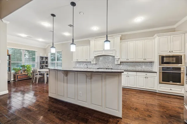 a kitchen with kitchen island granite countertop a sink a counter space appliances and cabinets