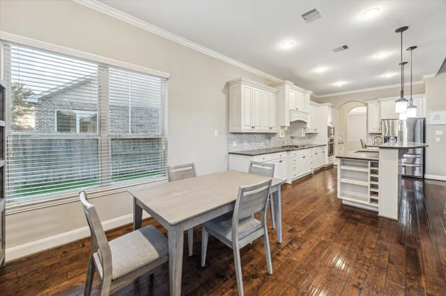 a kitchen with kitchen island a dining table chairs and white cabinets