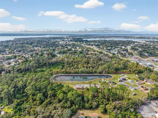 an aerial view of a residential houses with outdoor space and trees