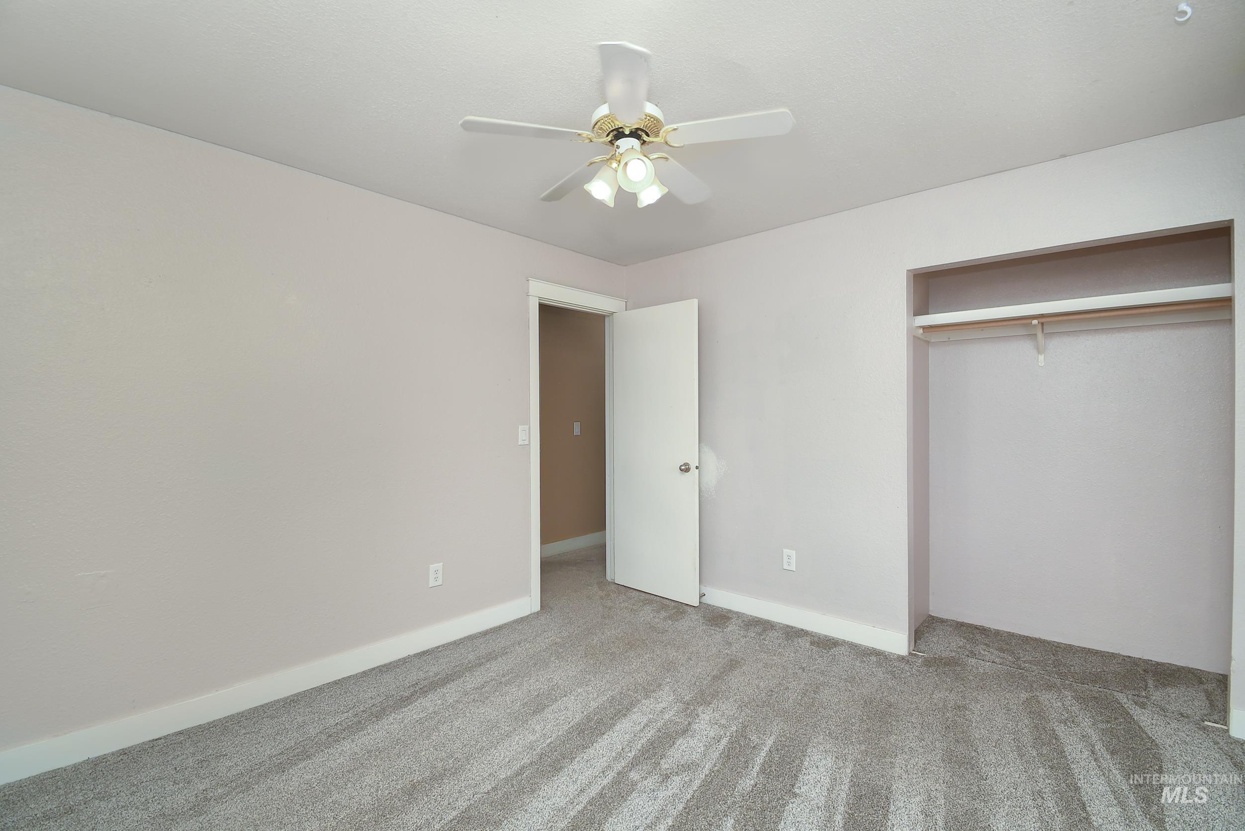 1108 East Ustick Road Caldwell, ID 83607 - Photo 19 of 30 Carpeted room with a ceiling fan, light gray walls, an open doorway with white trim, and a built-in closet with a hanging rod