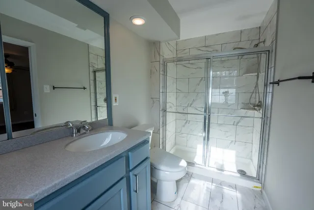 a bathroom with a shower sink vanity mirror and toilet