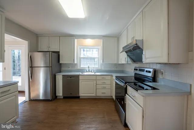 a kitchen with stainless steel appliances granite countertop a refrigerator sink and white cabinets