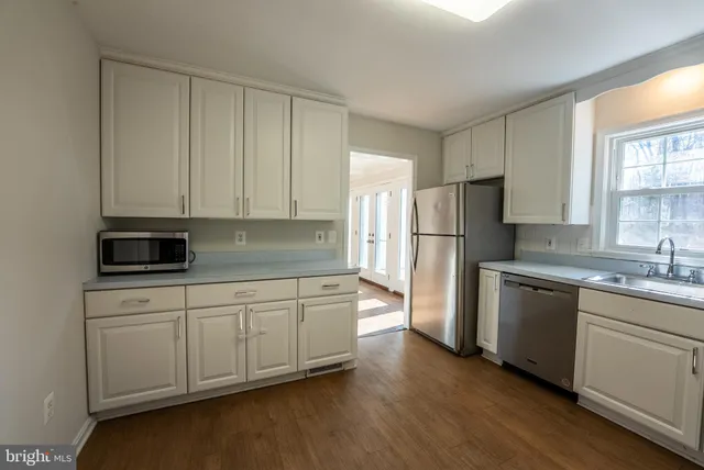 a kitchen with stainless steel appliances granite countertop a refrigerator sink and white cabinets