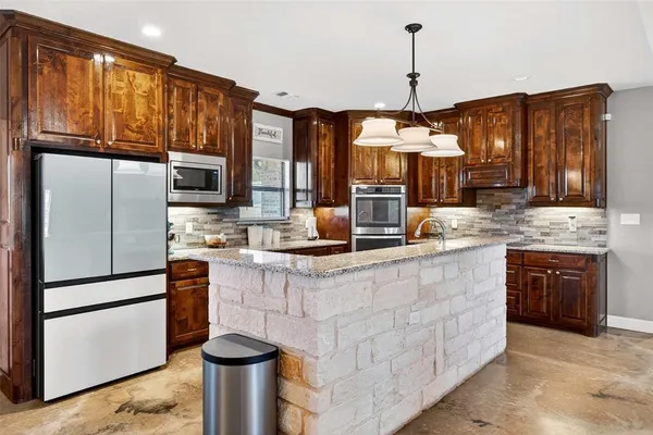 a kitchen with stainless steel appliances granite countertop a sink refrigerator stove and microwave