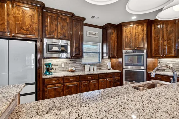 a kitchen with stainless steel appliances kitchen island granite countertop a refrigerator stove top oven and sink