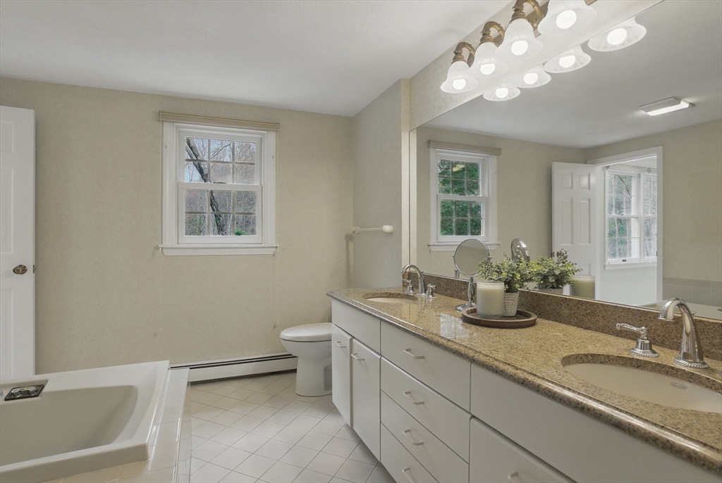 14 Harvard Drive Bedford, MA 01730 - Photo 24 of 40 a bathroom with a sink a large mirror and a toilet