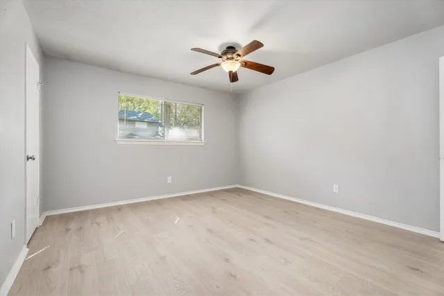 an empty room with a window and a fan