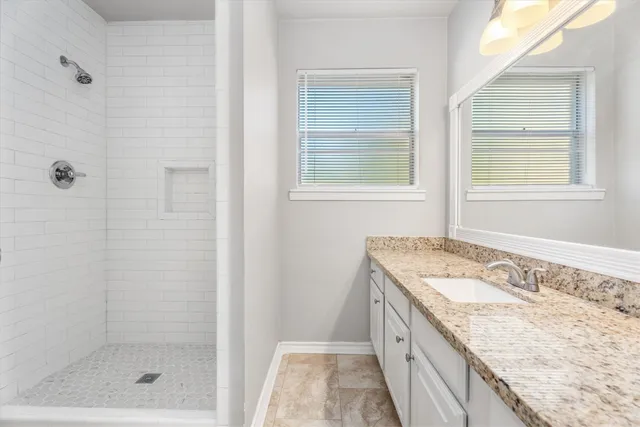 a bathroom with a granite countertop sink a mirror and shower