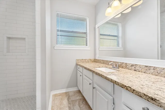 a bathroom with a granite countertop sink and a window