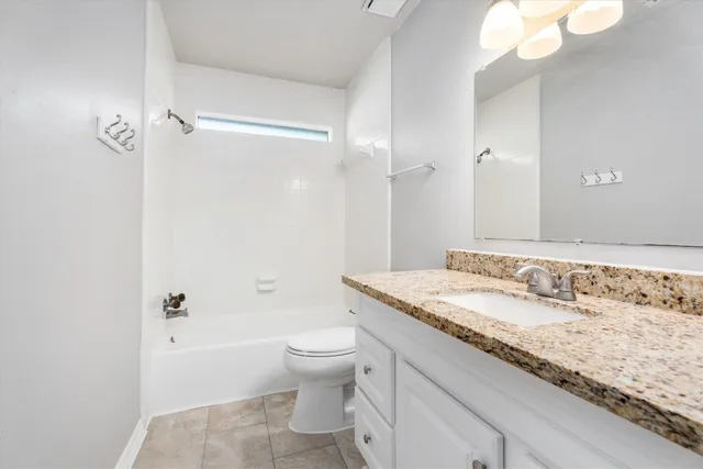 a bathroom with a granite countertop sink a toilet and shower