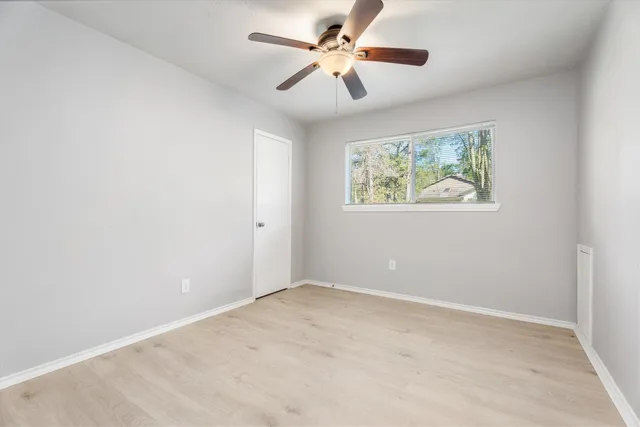 an empty room with windows and fan