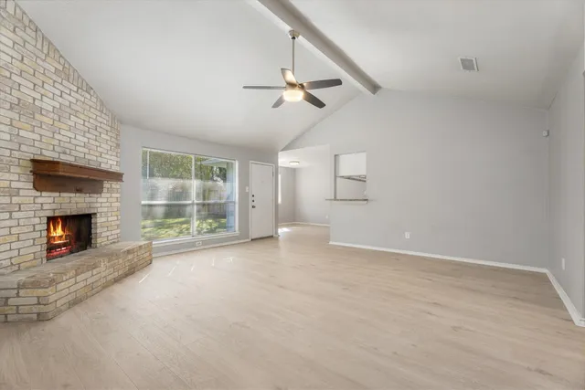 an empty room with windows and fireplace