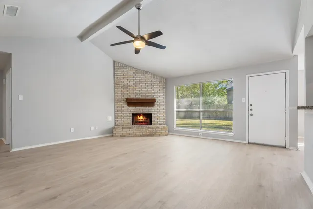 an empty room with chandelier fan and windows