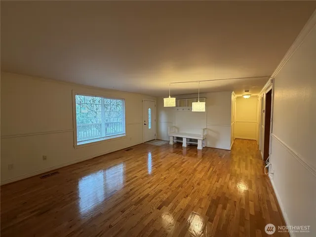 a view of empty room with wooden floor and furniture