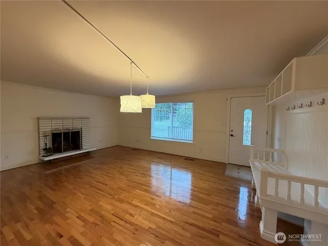 a view of an empty room with wooden floor and a fireplace