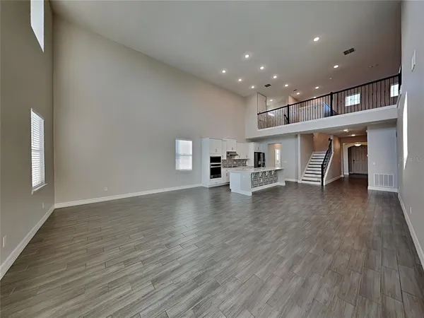an empty room with wooden floor and a kitchen