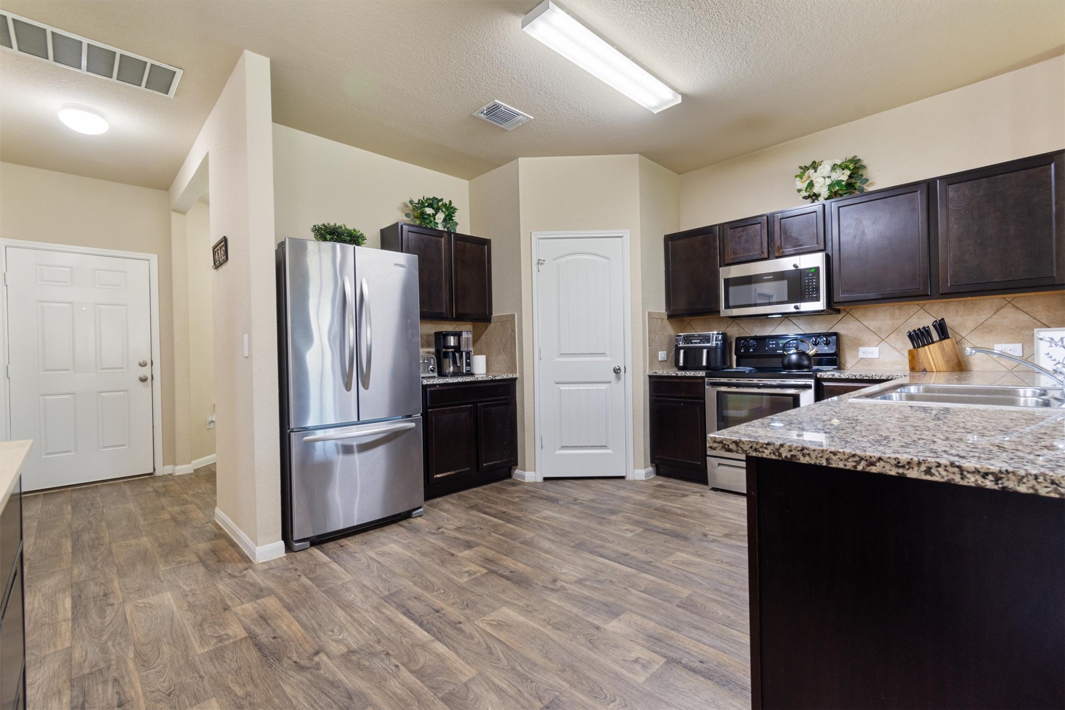 11620 Carbrook Road Manor, TX 78653 - Photo 11 of 40 a kitchen with granite countertop wooden cabinets a refrigerator and a sink