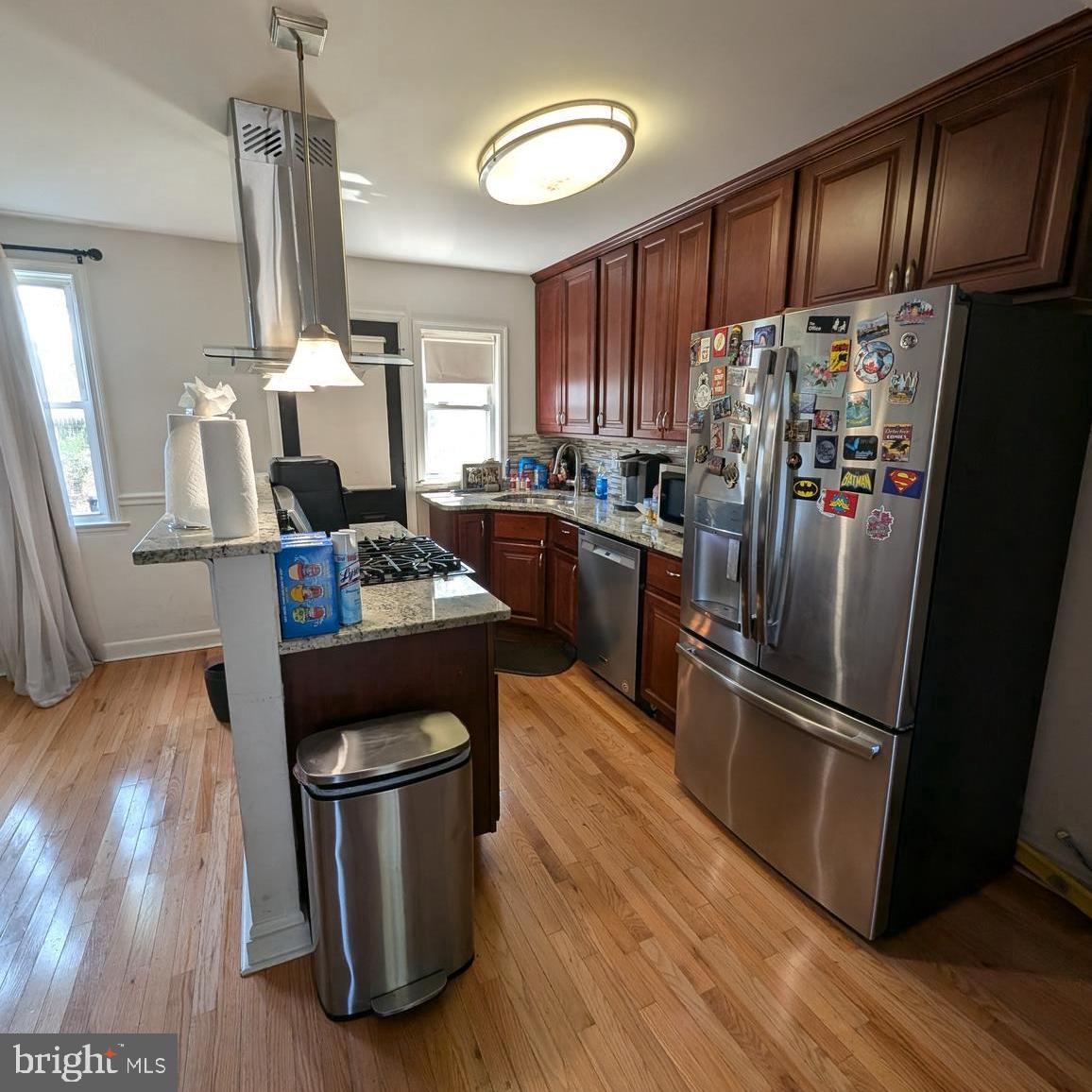 4219 Colborne Road Baltimore, MD 21229 - Photo 8 of 22 a kitchen with stainless steel appliances granite countertop a refrigerator a stove a sink dishwasher and a dining table with wooden floor