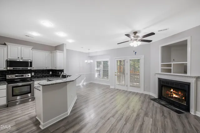 a kitchen with stainless steel appliances granite countertop a stove top oven a sink dishwasher and a fireplace with wooden floor