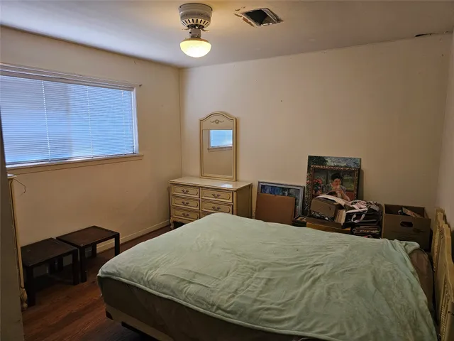 a bedroom with a bed and a lamp on dresser