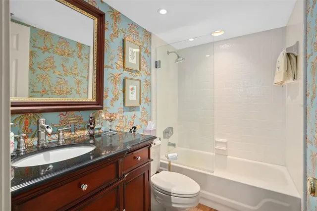 a bathroom with a granite countertop sink a toilet and bathtub