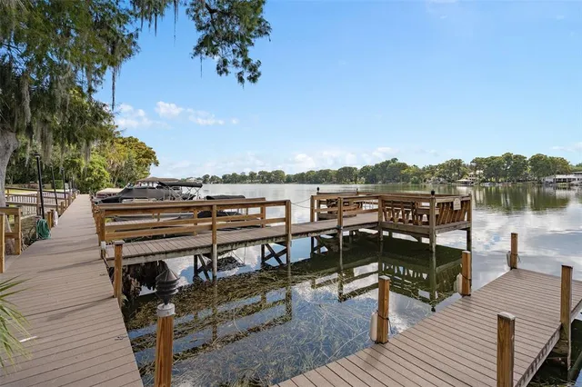 a view of a roof deck with table and chairs a barbeque with wooden floor and fence