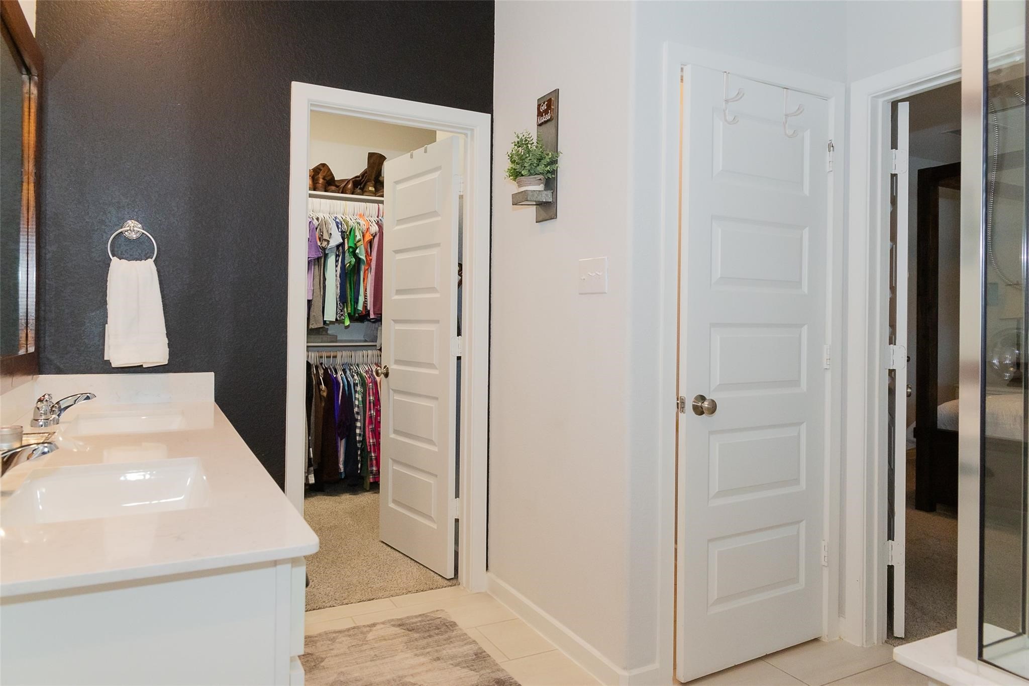 385 Weimer Lagoon Road La Porte, TX 77571 - Photo 13 of 22 The En Suite showcases a modern bathroom with dual sinks, a dark accent wall, and a towel rack. The space leads to a walk-in closet and additional storage space