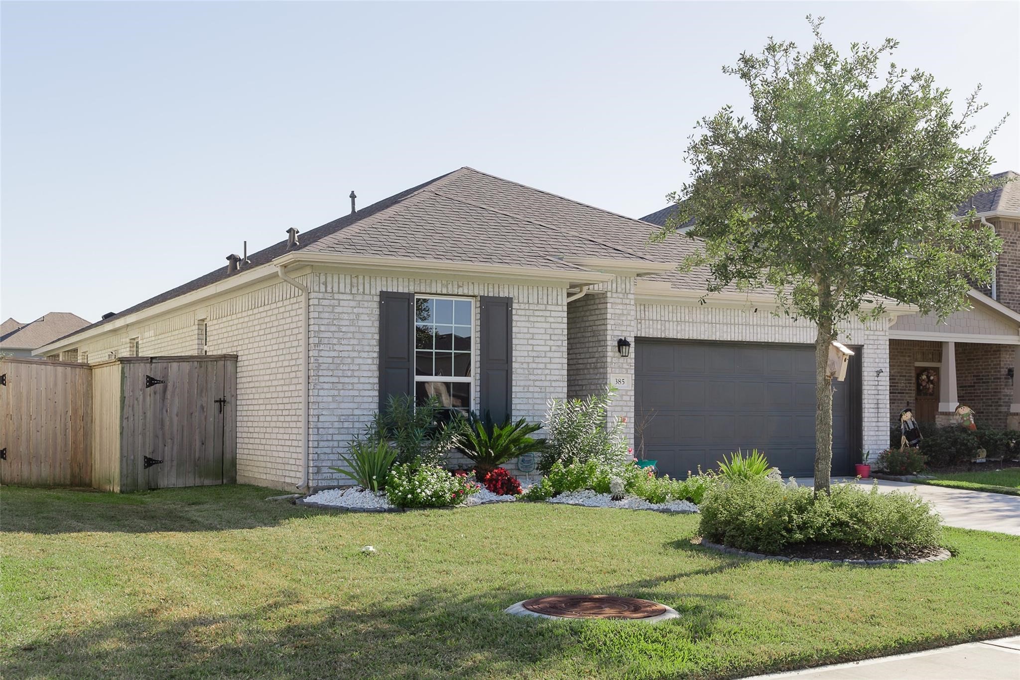 385 Weimer Lagoon Road La Porte, TX 77571 - Photo 2 of 22 This charming single-story home features a light brick exterior, a well-maintained front yard with mature landscaping, and a spacious two-car garage.