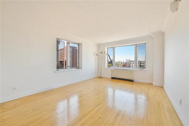 a view of an empty room with a window and wooden floor