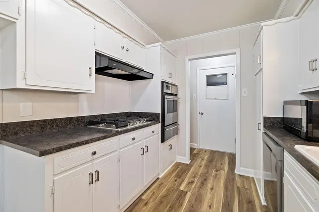 a large kitchen with a center island stainless steel appliances cabinets and a window