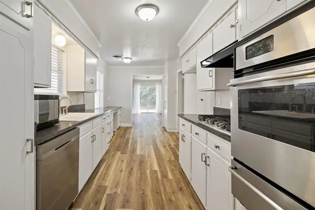 a kitchen with granite countertop a refrigerator and wooden floor