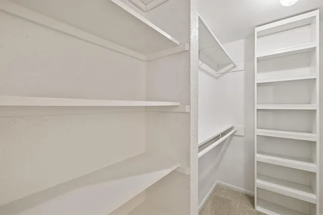 an empty room with windows and chandelier fan