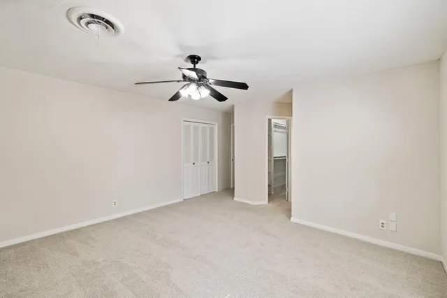 an empty room with windows and fan