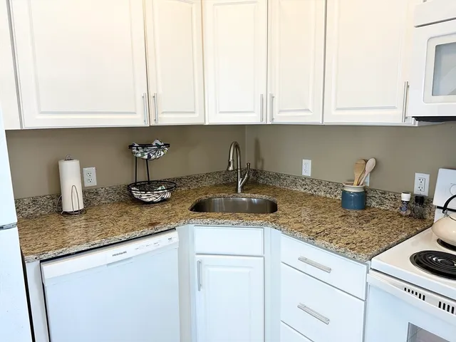 a kitchen with stainless steel appliances granite countertop white cabinets sink and stove